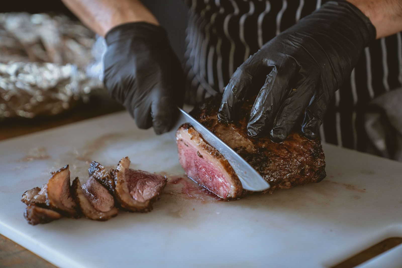Kuhar reže pečen zrezek, prizor ponazarja carnivore dieto, ki jo je obravnavala študija o črevesnem mikrobiomu.