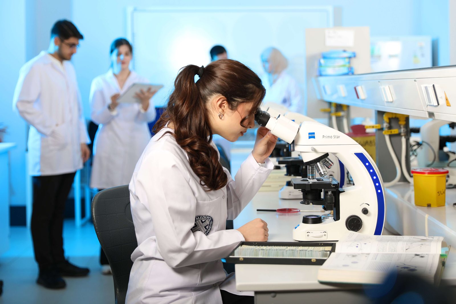 Raziskovalka za mikroskopom v laboratoriju proučuje biološke vzorce.